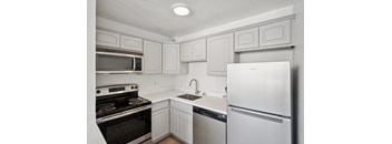 A white kitchen with a stove, oven, and refrigerator.