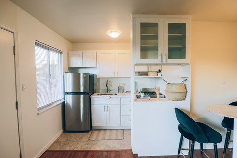 A kitchen with white cabinets and a stainless steel refrigerator.