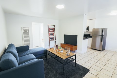 A living room with a blue couch and a black coffee table.