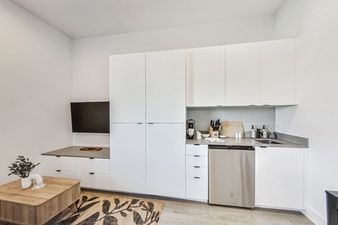 A modern kitchen with white cabinets and a wooden coffee table.