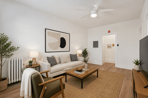A living room with a white couch, a brown rug, and a painting on the wall.