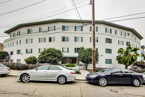 Two cars parked in front of a white building.
