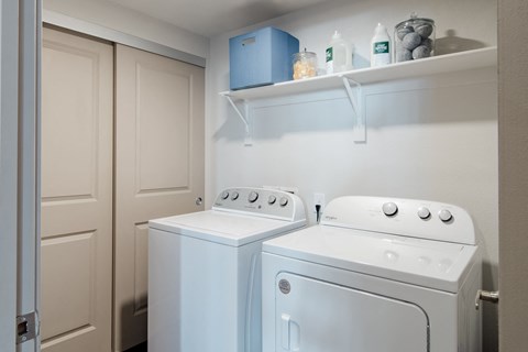 a white washer and dryer in a small laundry room with a shelf above at Parkside at Littleton Village, Littleton, CO