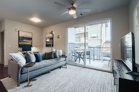 a living room with a couch and a sliding glass door to a balcony at Parkside at Littleton Village, Littleton