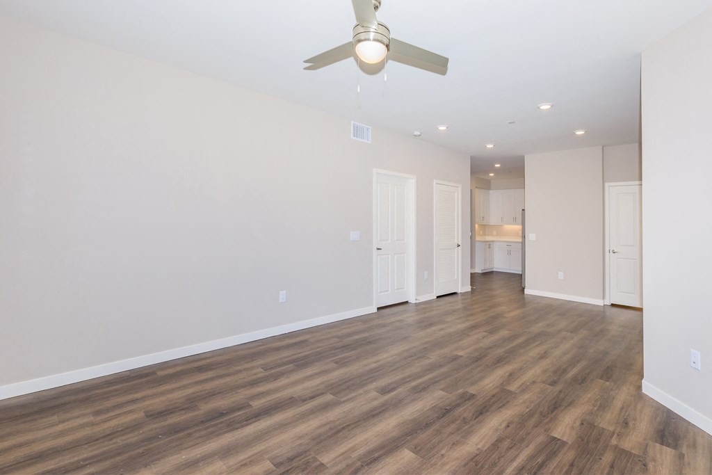 a living room with white walls and a ceiling fan