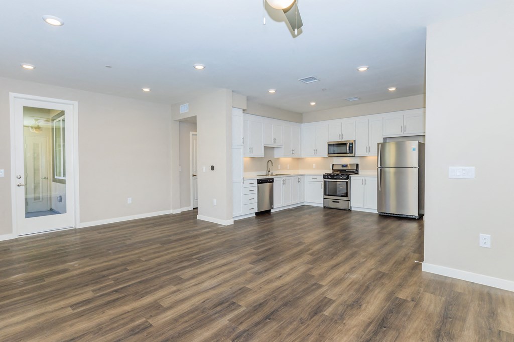 an empty kitchen with white cabinets and a stainless steel refrigerator and stove