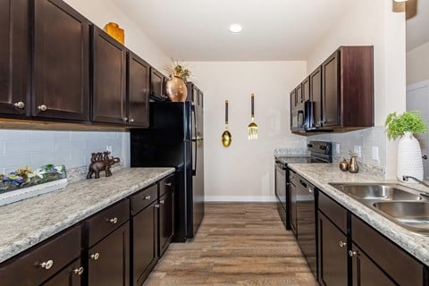 A kitchen with dark brown cabinets and a black refrigerator.