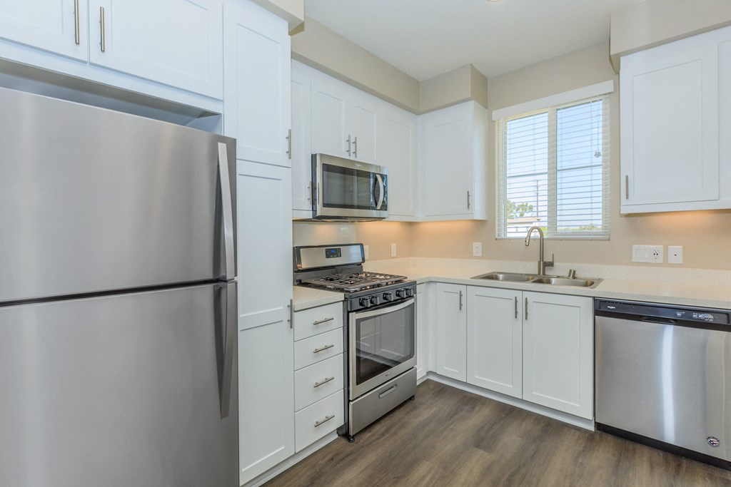 an empty kitchen with stainless steel appliances and white cabinets