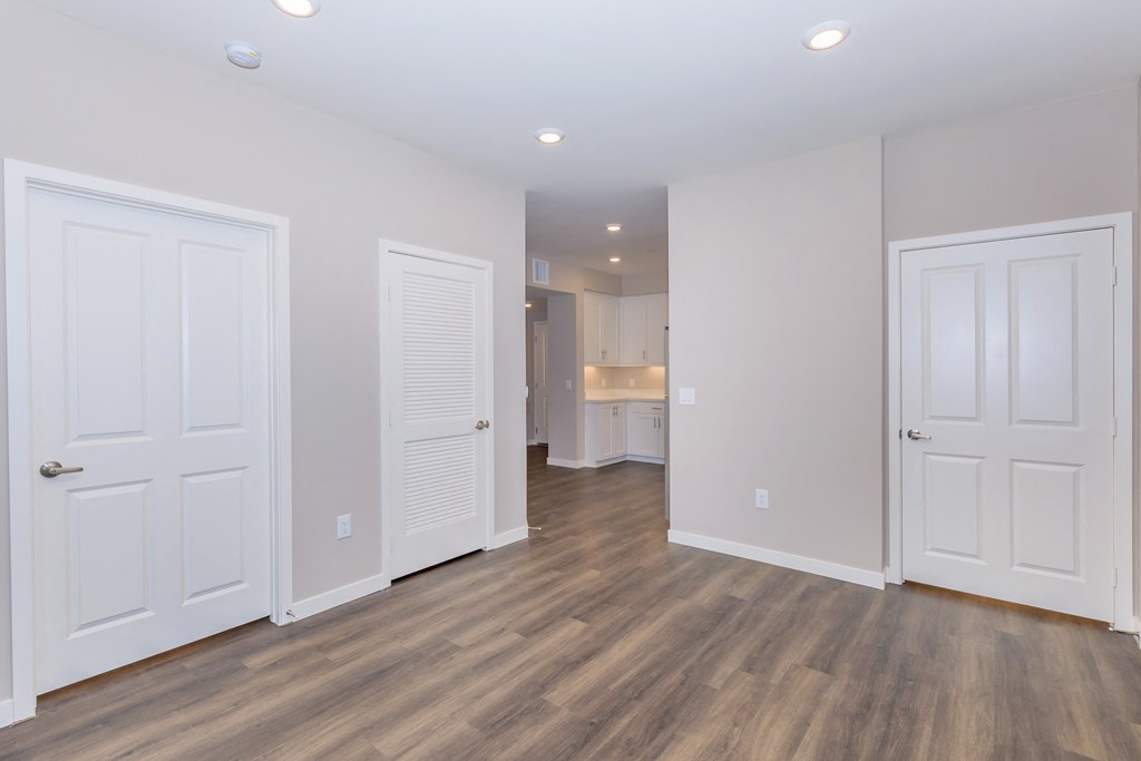 a living room with white doors and a hallway to a kitchen