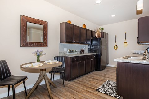 A kitchen with a table and chairs and a fridge.