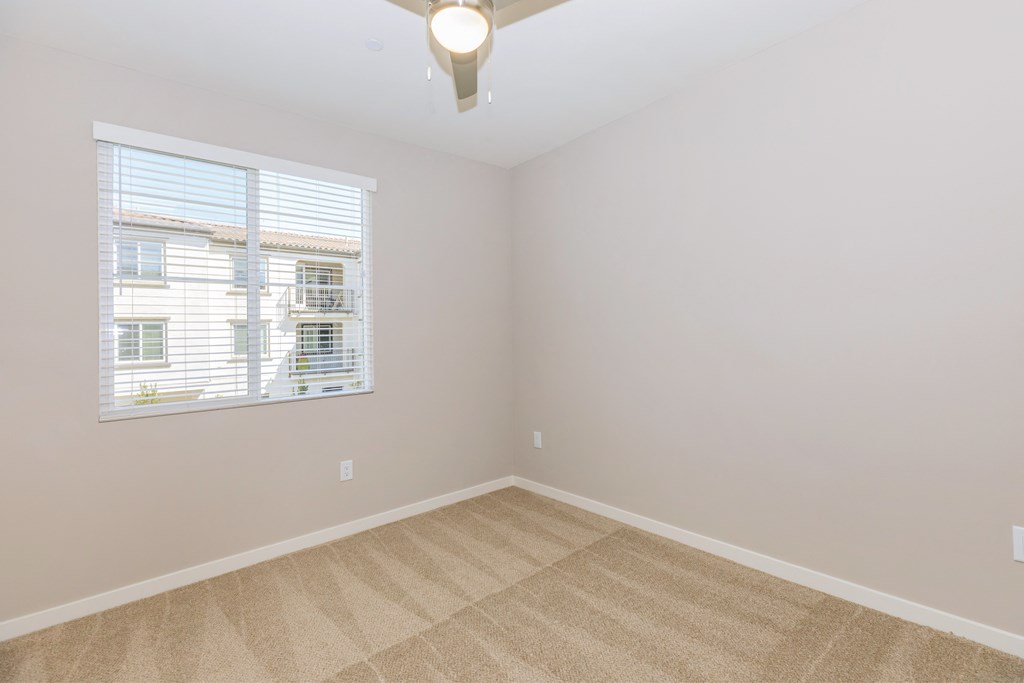 an empty living room with a window and carpet