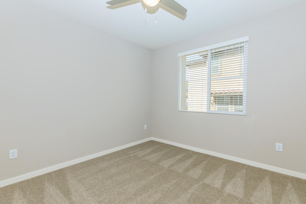 an empty room with a window and a ceiling fan