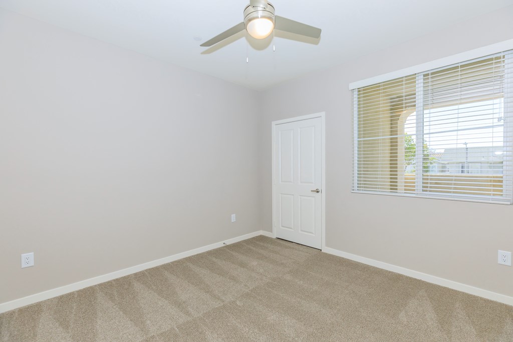an empty bedroom with a ceiling fan and a window
