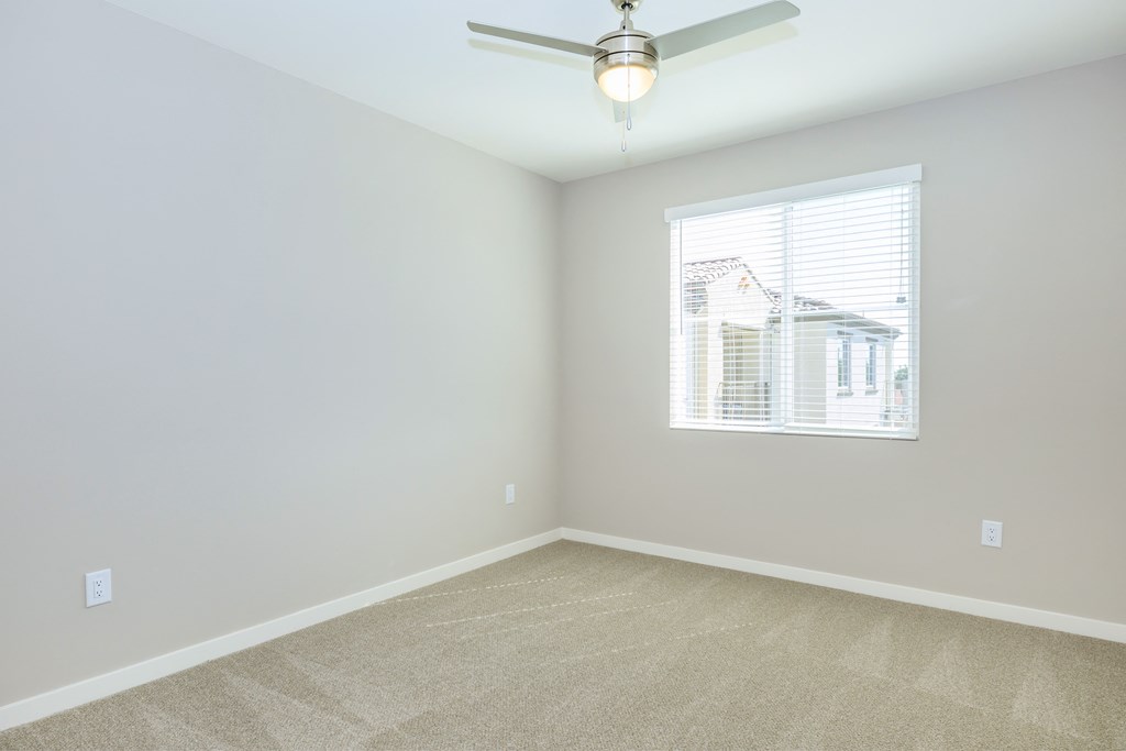 an empty room with a ceiling fan and a window
