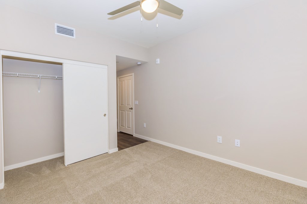 a spacious living room with a ceiling fan and a closet