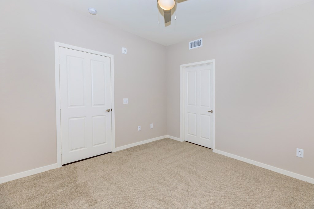 a bedroom with two doors and a carpeted floor