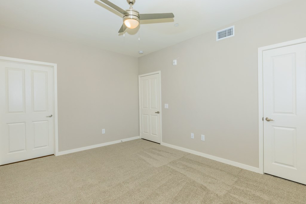 a bedroom with two doors and a ceiling fan