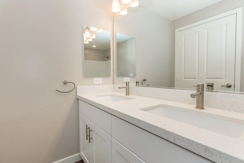 a white bathroom with two sinks and a mirror
