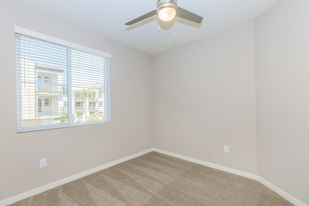 an empty bedroom with a ceiling fan and a window