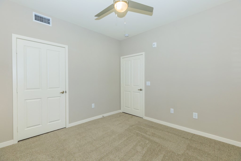 a empty room with two doors and a ceiling fan