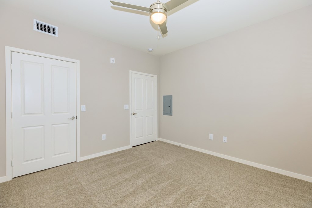 a empty room with two doors and a ceiling fan
