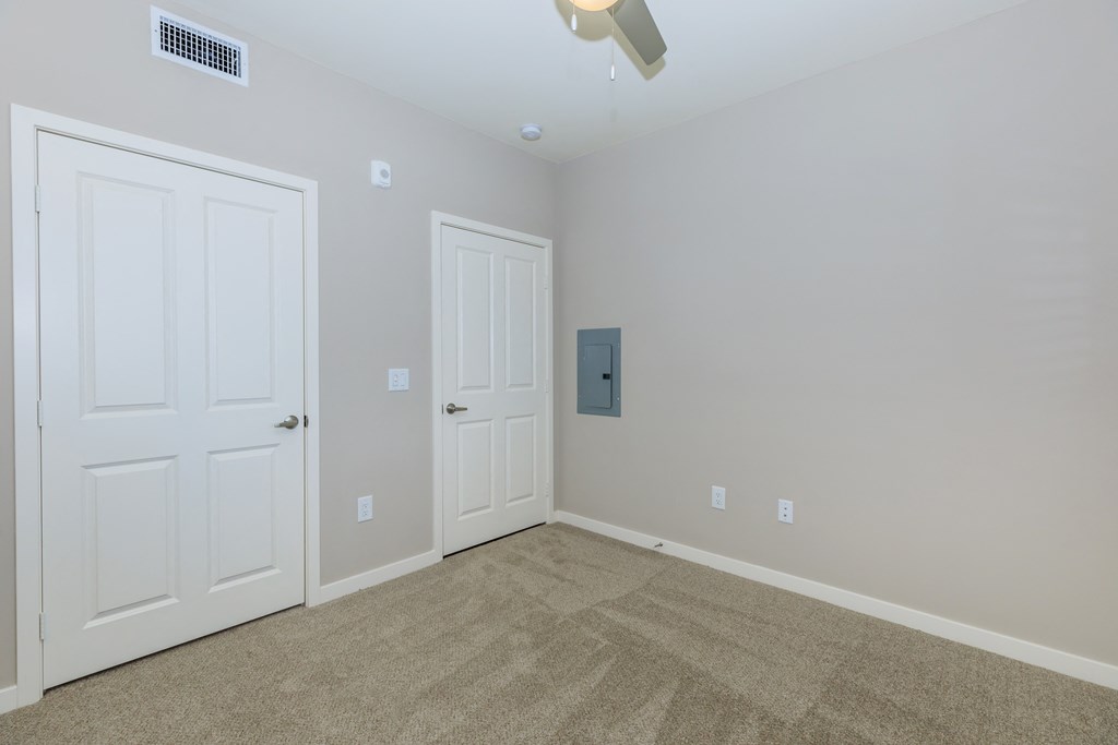 an empty room with two doors and a carpeted floor