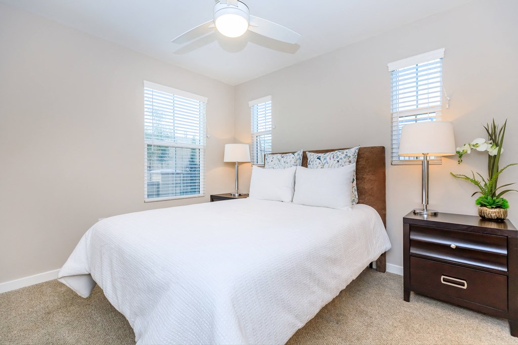 a bedroom with a large white bed and a ceiling fan