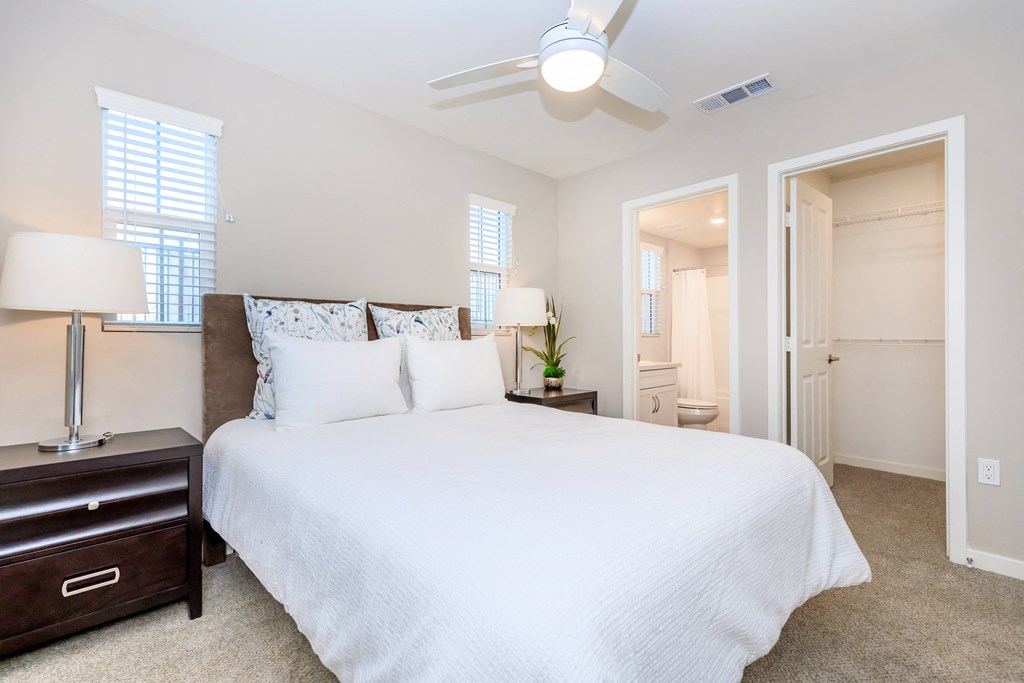 a bedroom with a large white bed and a ceiling fan