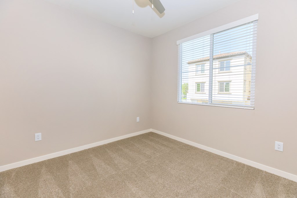 an empty bedroom with a window and carpet
