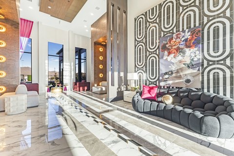 A modern living room with a long grey couch and a large painting on the wall.