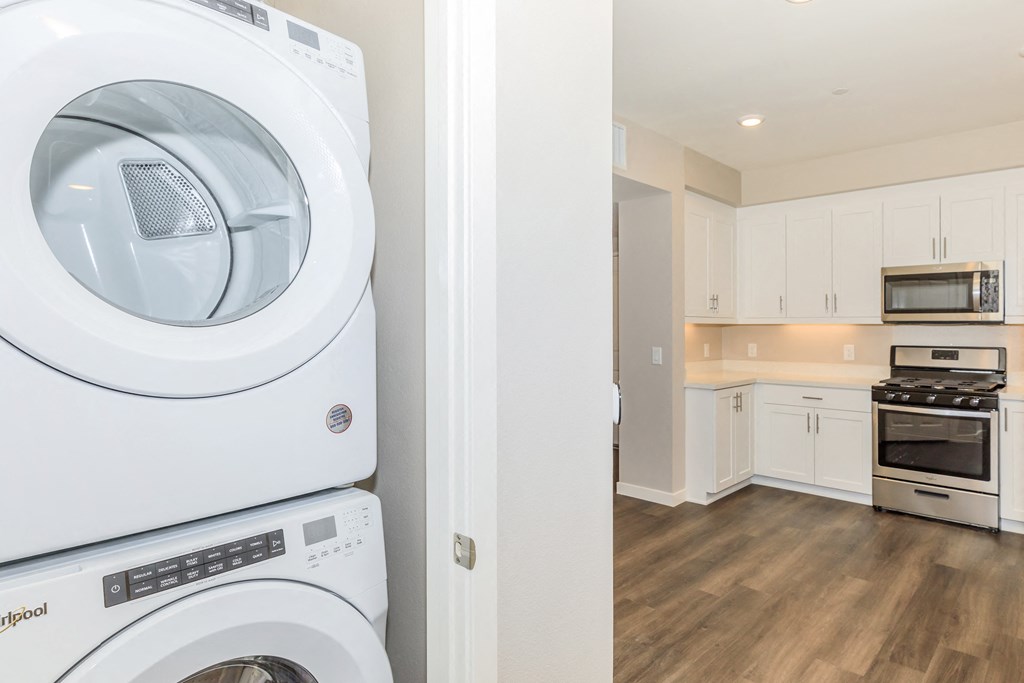 a white washer and dryer in a kitchen with white cabinets