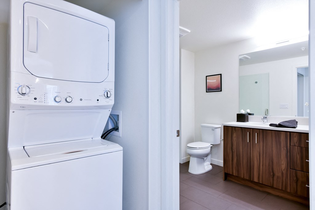 a washer and dryer in a bathroom with a toilet and a sink
