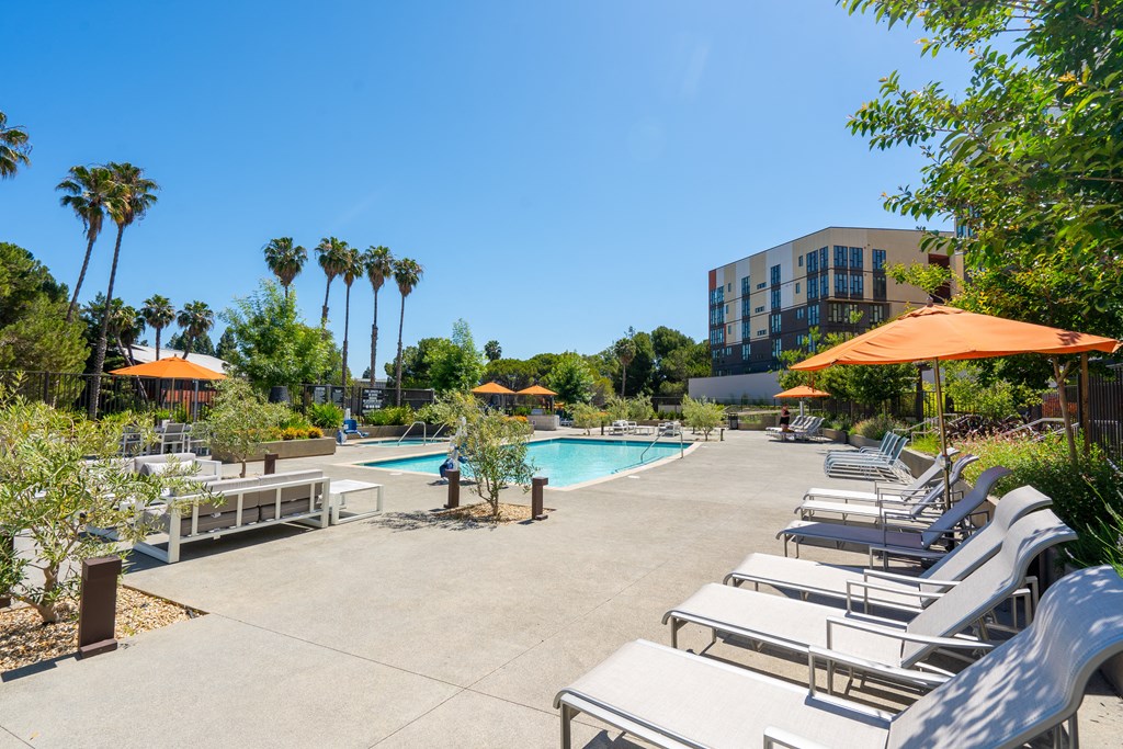 a swimming pool with chaise lounge chairs and umbrellas