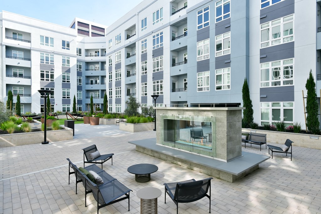 a patio with a fire pit in front of an apartment building
