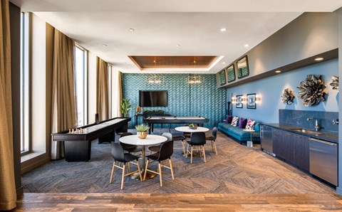 A modern living room with a pool table and a kitchen area.