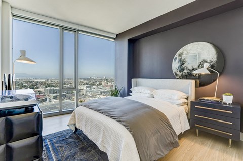 A modern bedroom with a large bed and a view of the city.