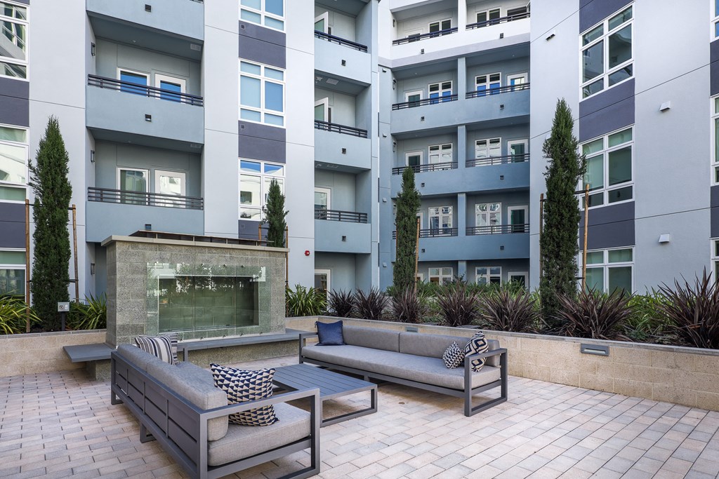a patio with couches and a fire pit in front of an apartment building