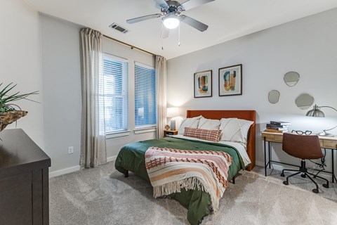 A bedroom with a bed, desk, and chair.