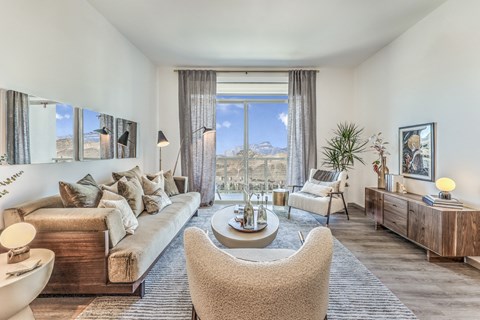 A well-lit, modern living room with a large window and a view of the mountains.