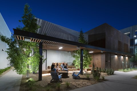 A modern building with a group of people sitting outside under a roof.