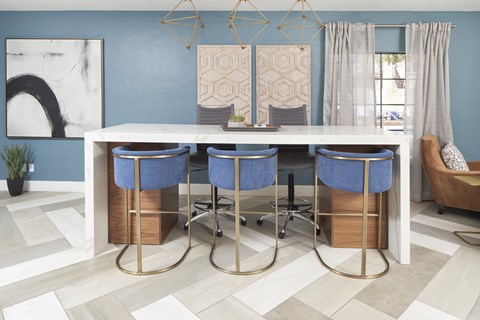 a kitchen with a marble counter top and blue bar stools