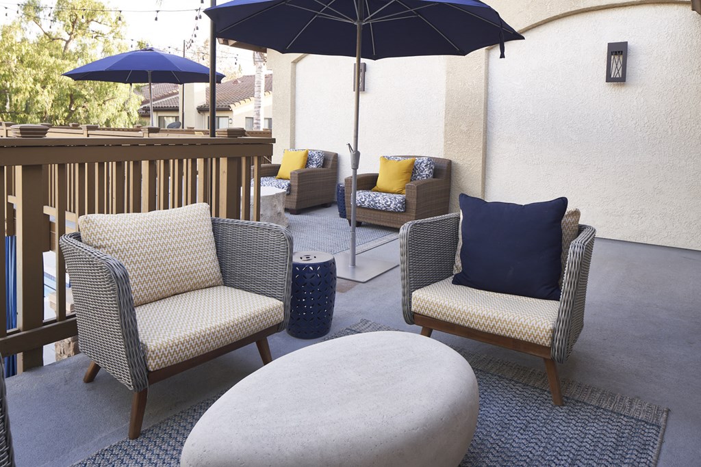 Apartments For Rent In Thousand Oaks, CA - The Knolls - Outdoor Community Balcony Space With Plush Seating, Tables, And Umbrellas