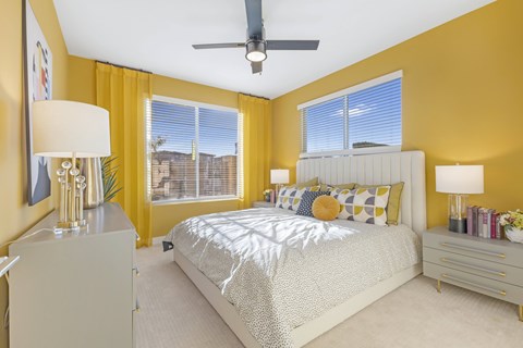 A bedroom with a bed, nightstands, and a ceiling fan.