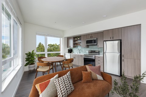 A modern kitchen with a brown couch and a dining table.