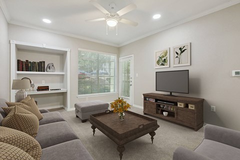 North Austin, TX, Pet-Friendly Apartments - Museo Channings Mark - Living Room With Carpet Flooring, Sofa, Stool, Armchair, Coffee Table With Flowers, Built-In Shelves, Ceiling Fan, And Large Window.