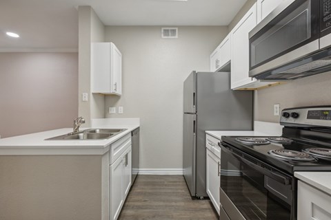 A kitchen with a black stove top oven and a white sink.