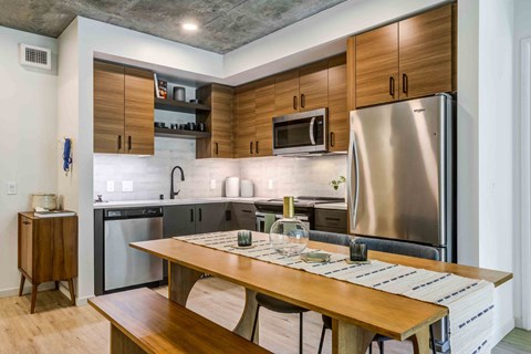 A modern kitchen with a wooden table and stainless steel appliances.