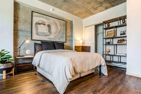 A bedroom with a large bed and a painting on the wall.