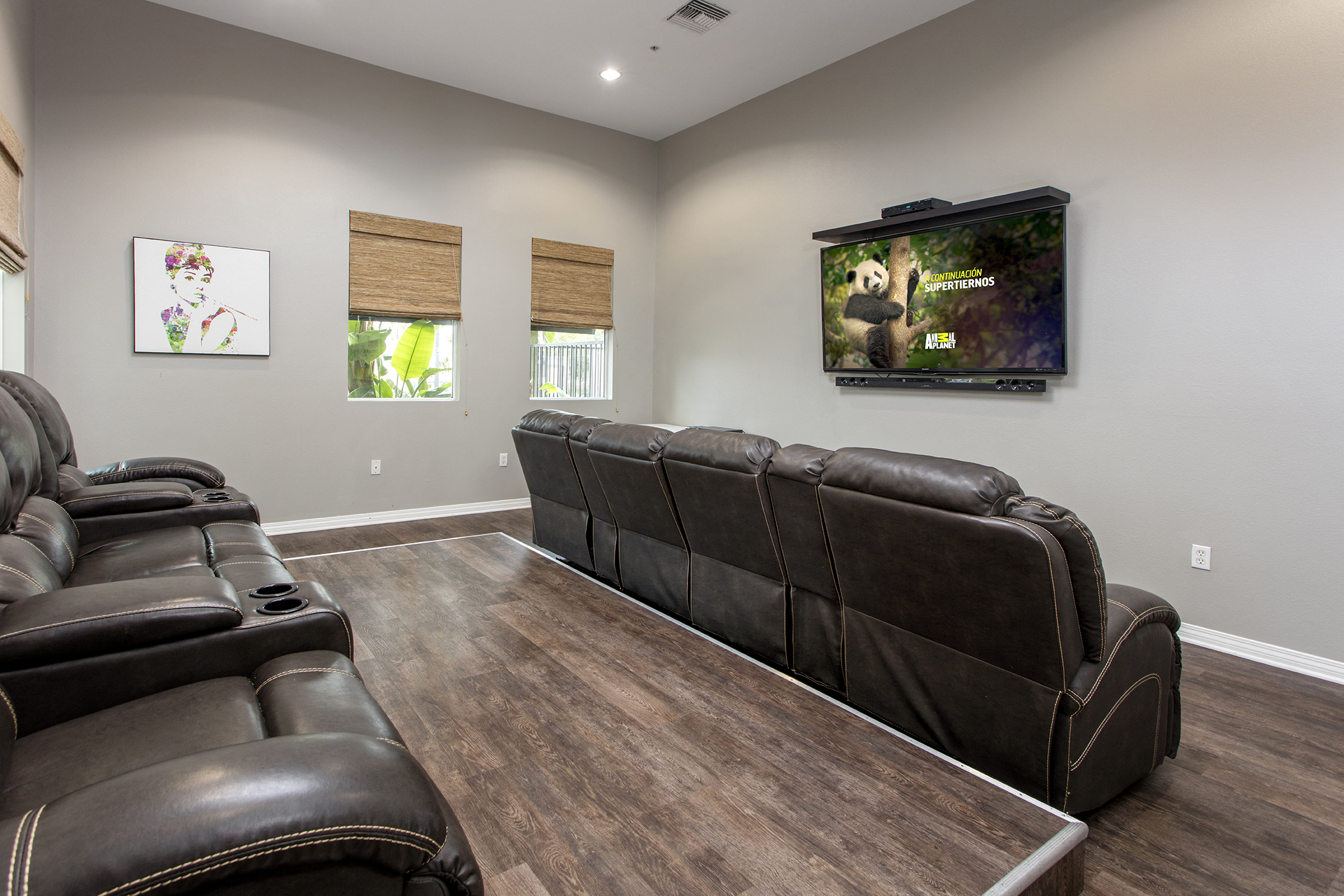 A living room with a brown leather couch and a flat screen TV mounted on the wall.