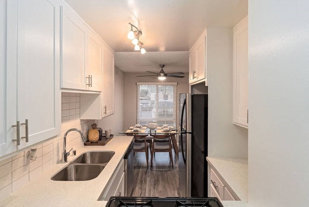 A kitchen with white cabinets and a black refrigerator at Nola 624 Apartments, West Covina, CA, 91790